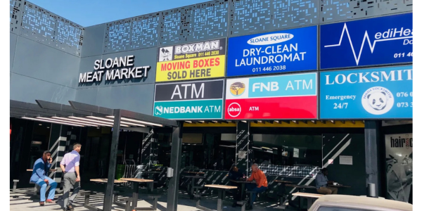 A shopping center facade with several business signs, including Sloane Meat Market